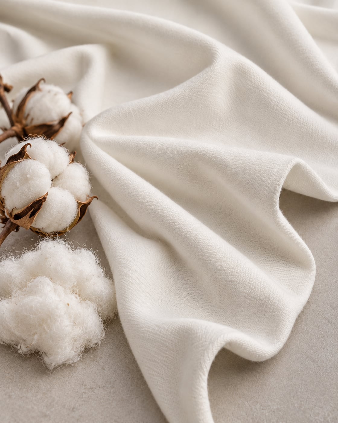 Malha Pima Cotton off-white em dobras, com capulhos de algodão ao lado