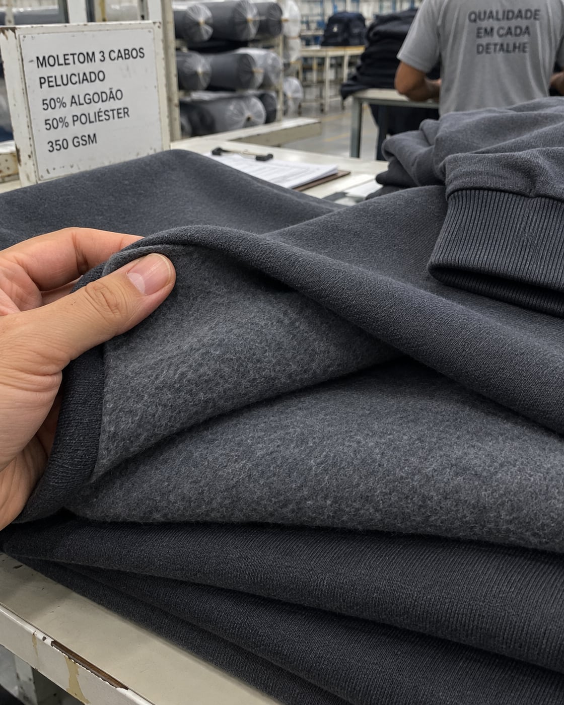 Mão sobre o Moletom 3 Cabos Peluciado com placa de identificação em ambiente de produção